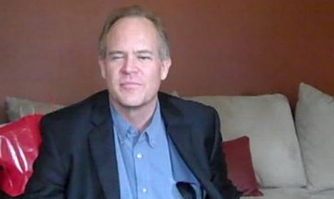 Steven Frazier seated on a couch wearing a dark blazer and blue shirt