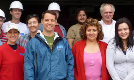 Group of volunteers and workers wearing hard hats and safety gear at a construction site