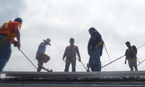 Construction workers installing solar panels on a rooftop in Carson, California