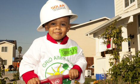 Child in hard hat and "GRID Alternatives" shirt at solar energy community event