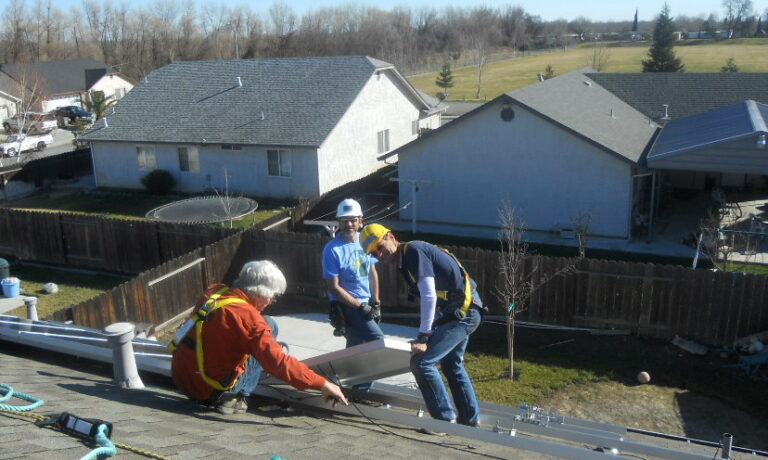 Three workers in safety gear installing roofing materials on a residential deck during a home improvement project