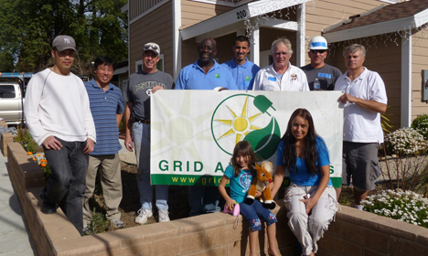 Group of volunteers holding Grid Alternatives banner at community workday event