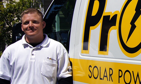 Marine Corps veteran in white polo beside yellow solar power vehicle
