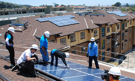 Workers installing solar panels on residential rooftop during Habitat for Humanity project