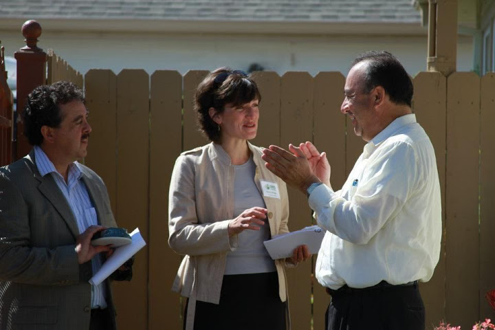 Three professionals discussing solar power project outdoors near fence