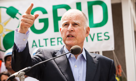 Gov. Brown speaks at microphone in front of green GRID Alternatives banner