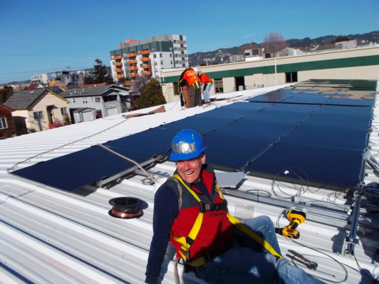 Worker in safety gear on rooftop with blue solar panels installed on building