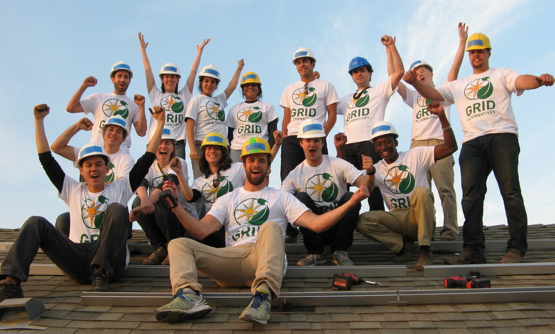 Team in GRID Alternatives shirts celebrates on rooftop after completing solar installation project