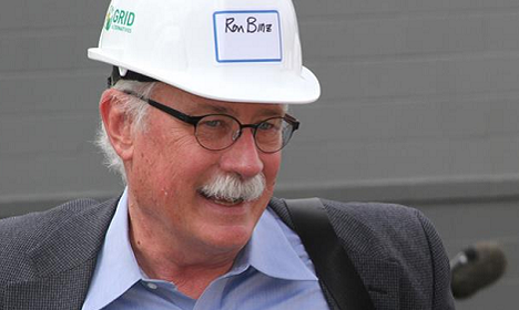 Man wearing hard hat labeled "Ron Binz" with glasses and mustache