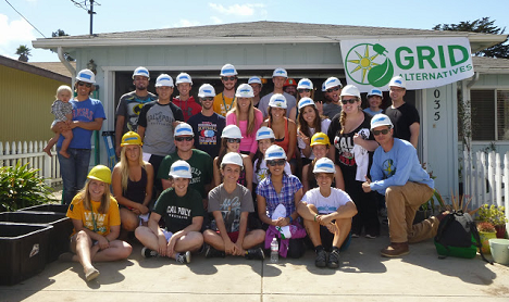 Group of volunteers wearing hard hats standing in front of a GRID Alternatives building
