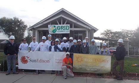 Group of workers in hard hats holding SunEdison and GRID banners in front of a building