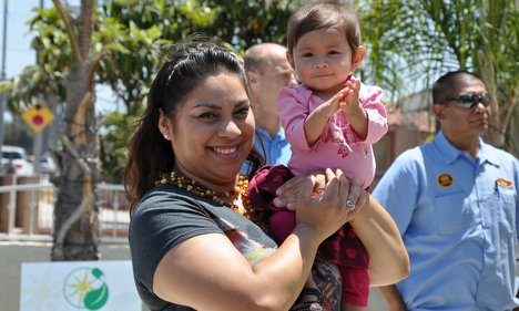 Woman holding toddler smiles at outdoor event celebrating Solar Equity Bill becoming law