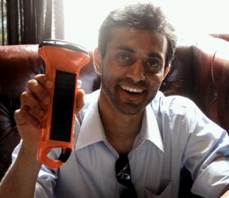 Man holding orange handheld device, smiling at camera in office chair