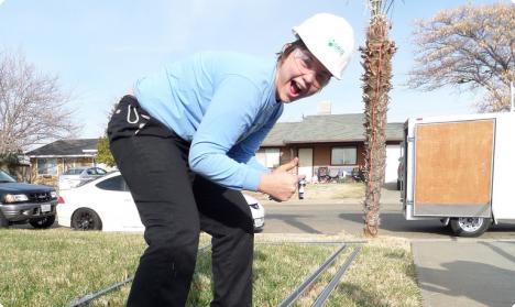 Man in hard hat and blue shirt installing solar panel on residential roof