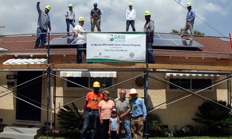 Workers and residents celebrate El Monte Affordable Solar Homes Program installation with solar panels on roof