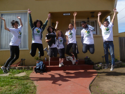 Group of young people jumping in the air wearing GRID Bay Area shirts in front of a yellow building