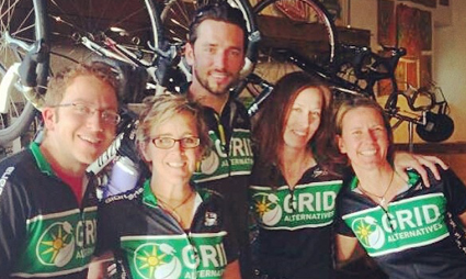 Five team members wearing GRID black shirts pose together in front of bikes indoors