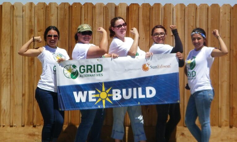 Five women flexing muscles while holding a "We Build" banner for GRID Alternatives and SunEdison