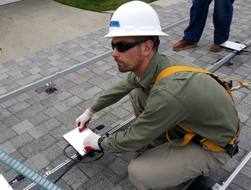 Worker in hard hat and safety gear performing roof inspection with clipboard and measuring tools