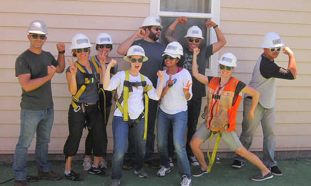 Group of young professionals wearing hard hats and safety vests posing together at a construction site event