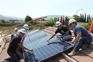 Workers installing solar panels on a residential rooftop during a community installation project