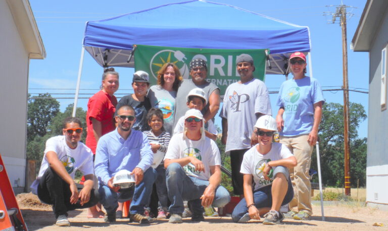 Group of volunteers under a blue tent at a solar installation event for Big Valley Rancheria