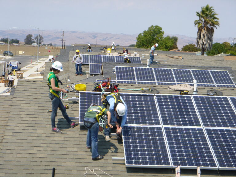 Workers installing solar panels on a residential roof during Solarthon 2014
