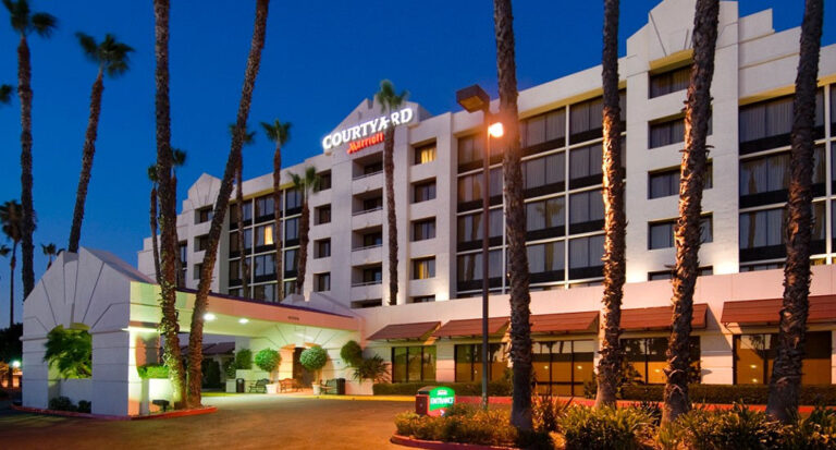 Courtyard by Marriott hotel at dusk with illuminated palm trees and entrance