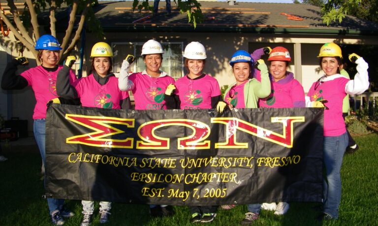 Eight women in hard hats and pink shirts hold banner for Sigma Omega Nu, California State University Fresno Epsilon Chapter, established May 7, 2005