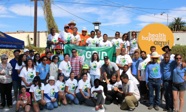Large group wearing GRID and health happens aquí shirts at community solar event