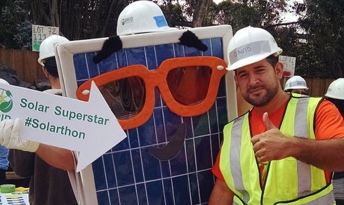 Construction worker in safety gear posing with oversized solar panel glasses at Solarthon event