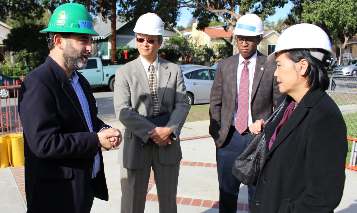 Congresswoman Judy Chu discusses solar project with construction workers and officials wearing hard hats at a job site