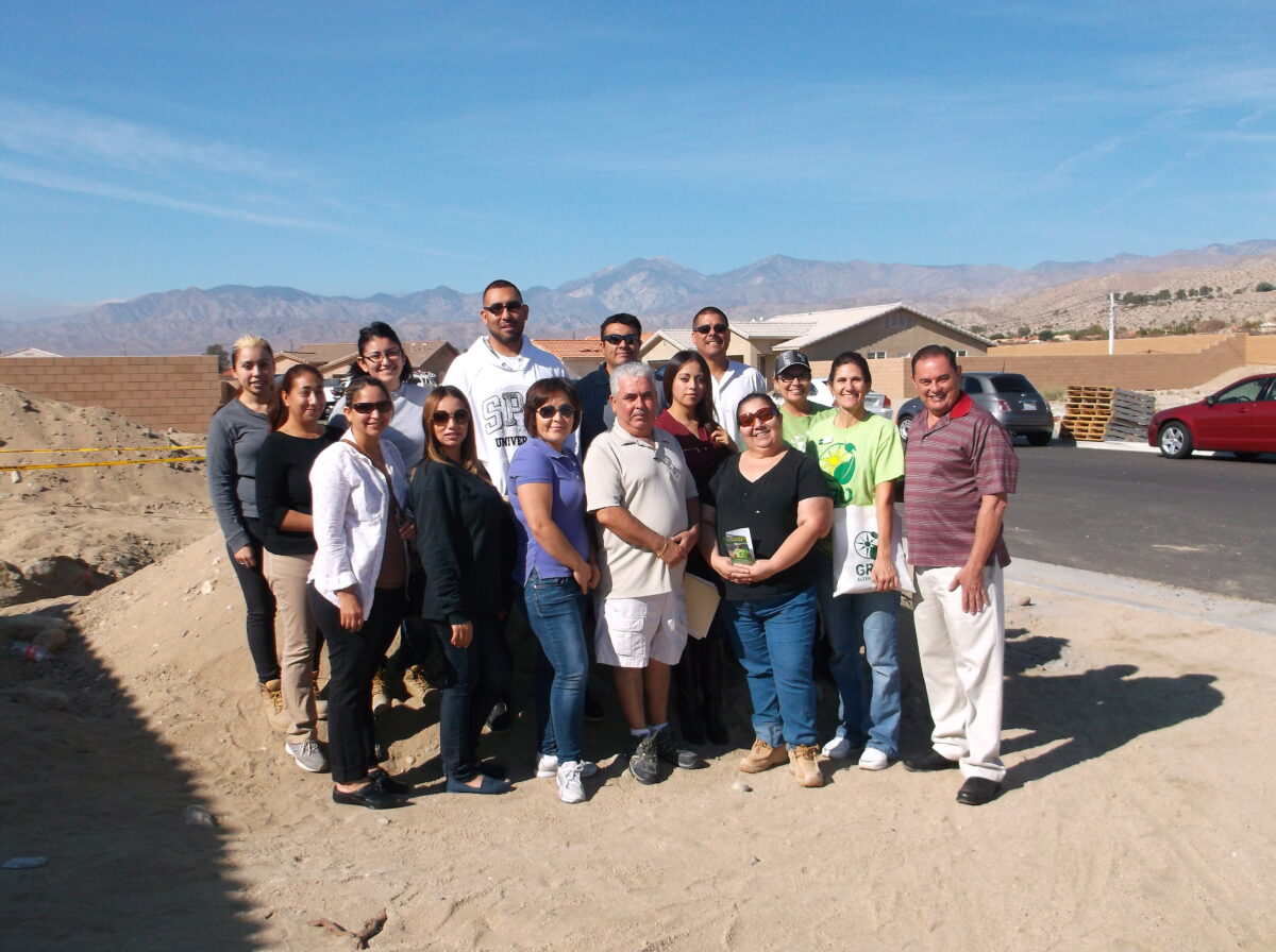 Group of people posing together outdoors in a desert landscape with mountains in background