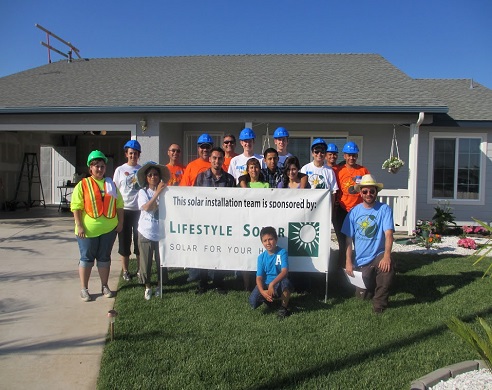 Solar installation team holding banner for Lifestyle Solar in front of residential home
