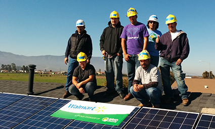 Group of workers in hard hats posing with solar panel at job training site