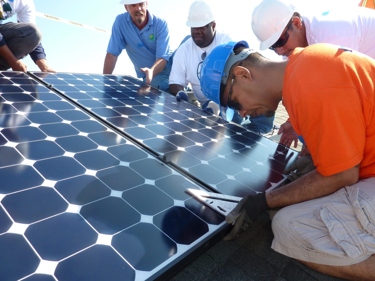 Multiple workers installing solar panels during a training or installation project outdoors