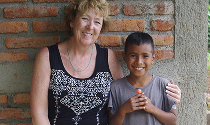 Two women smiling at camera against brick wall, representing volunteer mentorship