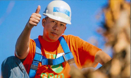 Construction worker in safety gear giving thumbs up against blue sky