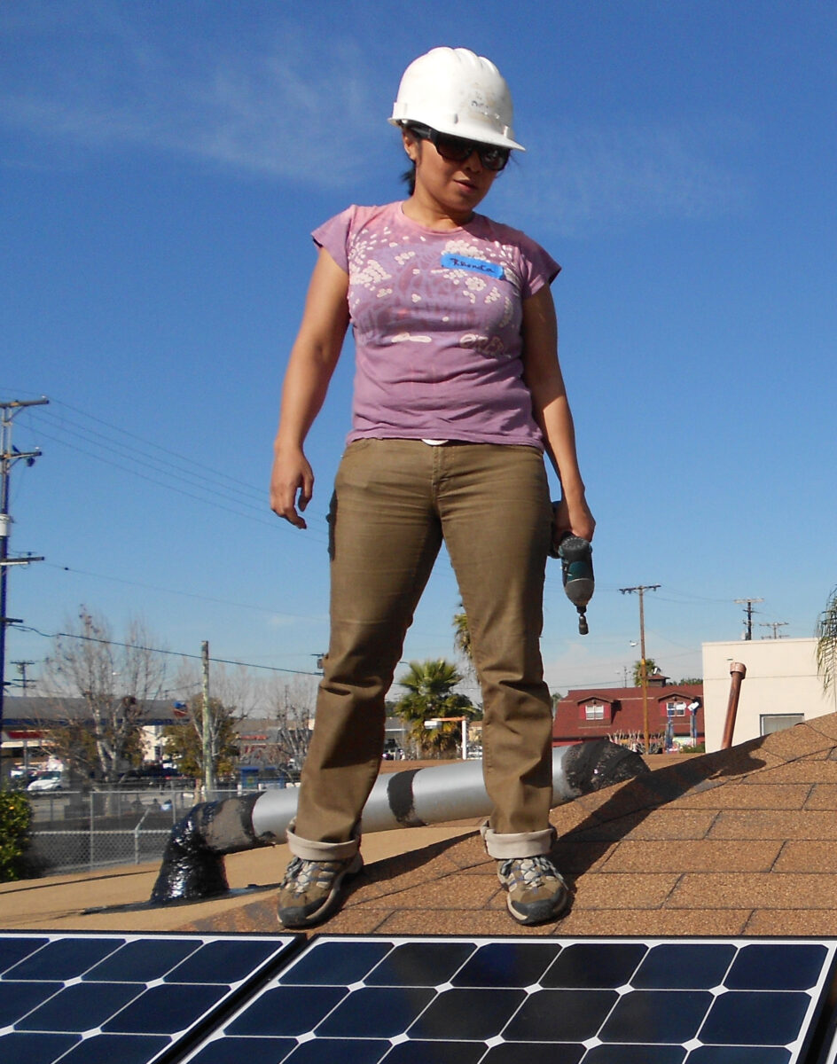 Woman in safety gear standing on solar panels at a construction site