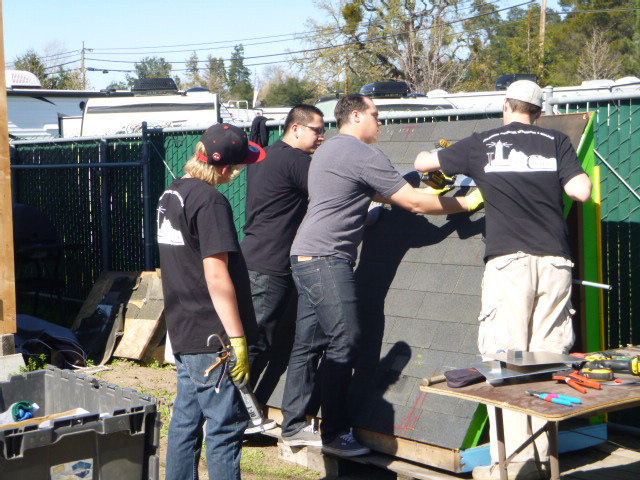 Group of five people assembling solar panels outdoors during a hands-on workshop