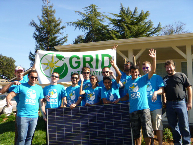 GRID Alternatives team holds solar panel while posing for group photo outdoors