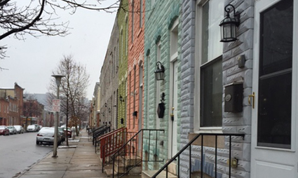 Row of historic row houses on urban street with bare trees and parked cars