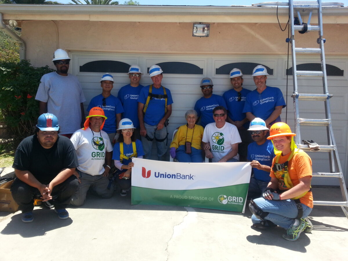 Union Bank volunteers hold GRID Alternatives banner at garage door during community service event