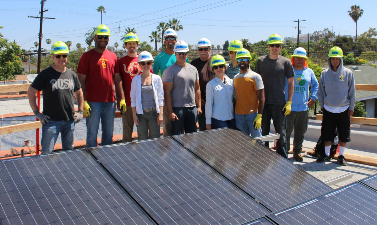Group of workers in hard hats and safety gear standing on a rooftop with solar panels during a corporate workday
