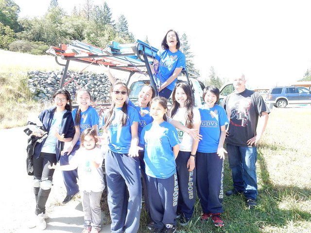 Group of young people in blue GRID shirts posing with solar installation equipment in Willits, California