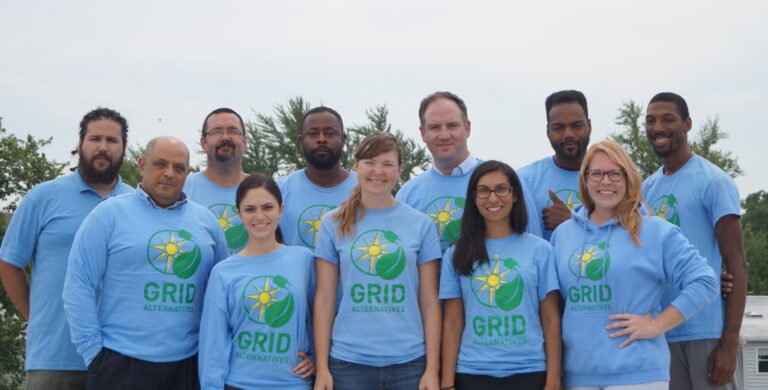 Team of 11 people wearing blue GRID Alternatives t-shirts pose together outdoors