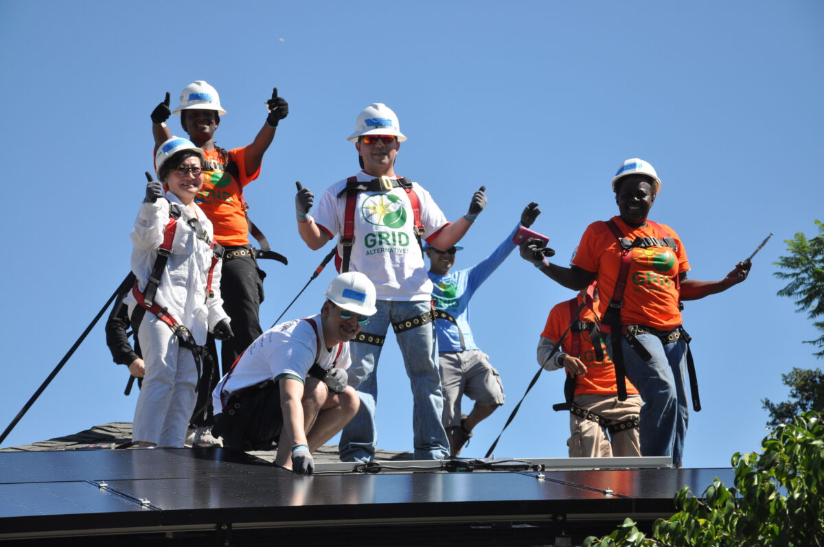 Workers celebrating on solar panel installation, wearing hard hats and safety gear