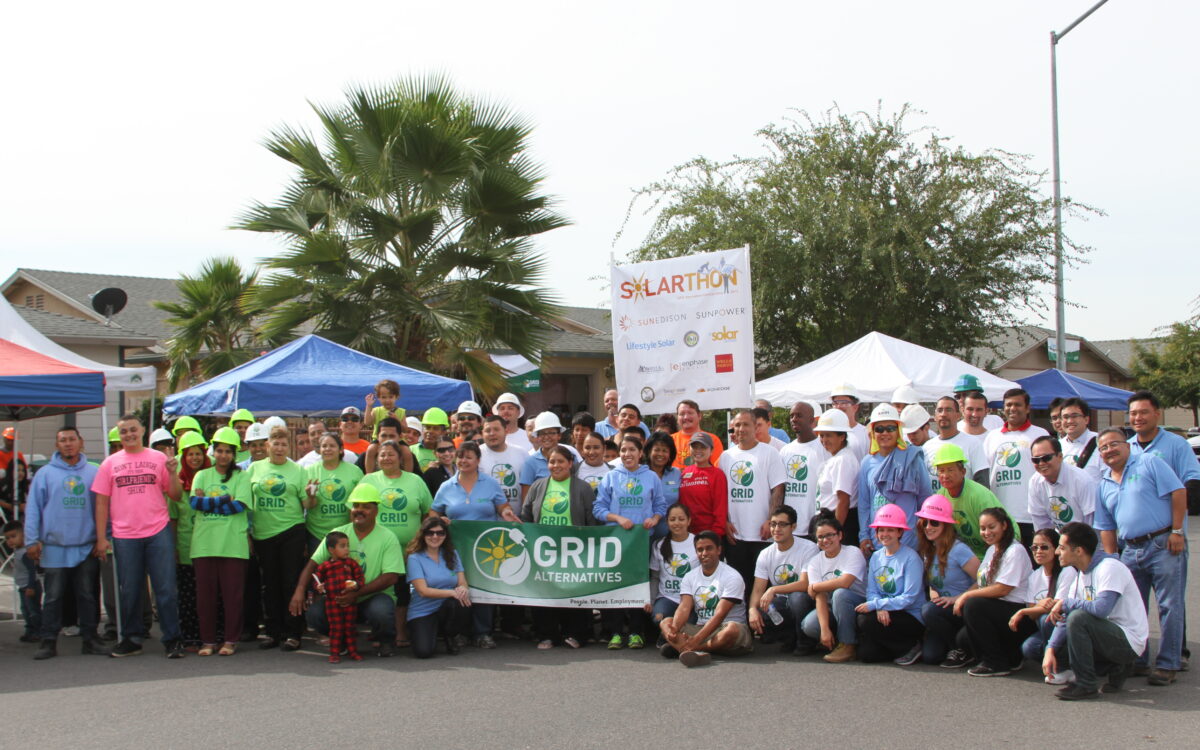 Large group of GRID Alternatives volunteers at 2015 Central Valley Solarthon event with banners and tents
