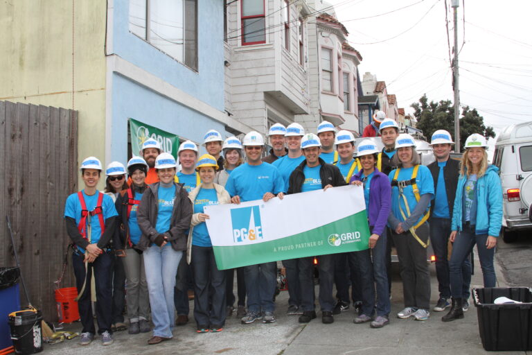 PG&E and GRID volunteers in hard hats holding banner at San Francisco community service event