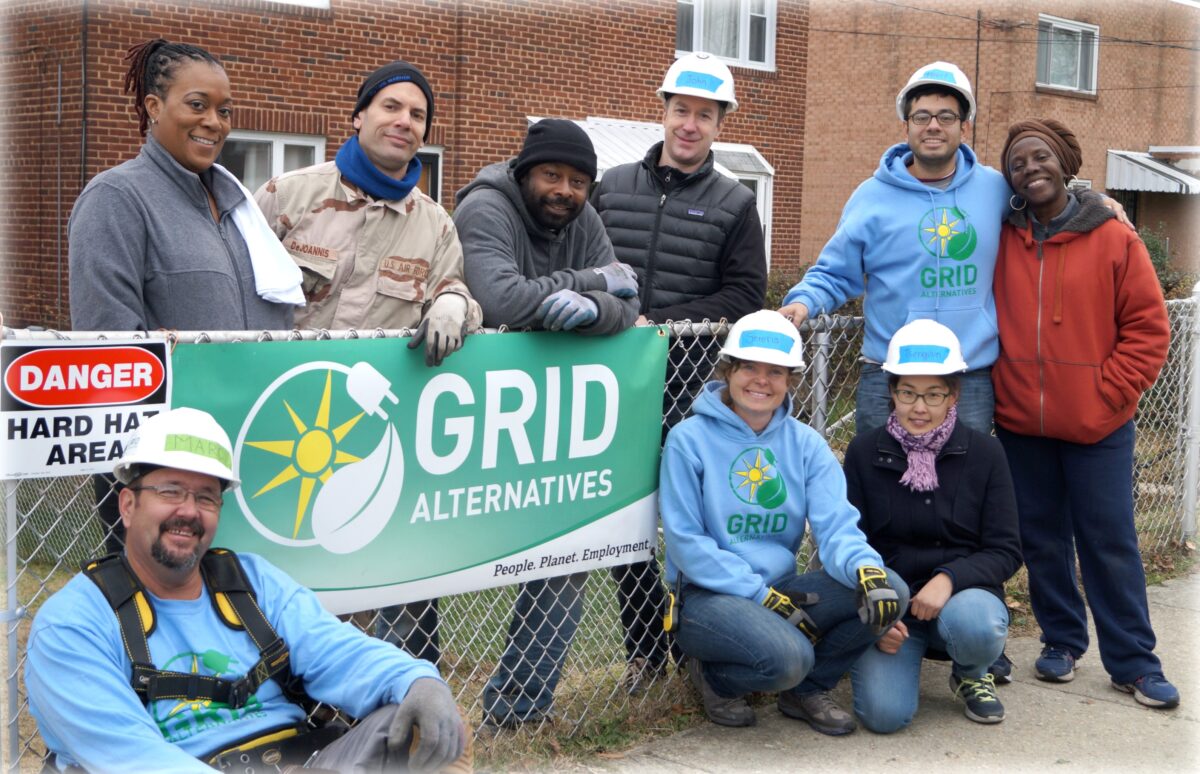 Group of workers holding GRID Alternatives banner at construction site